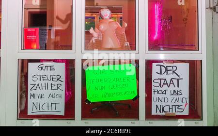 Hamburg, Deutschland. Juli 2020. Am Bordellfenster in der Herbertstraße hängen Spruchbänder mit den Aufschriften "gute Steuerzahler, das ist alles", "Wir sind Steuerzahler, jetzt werden wir im Stich gelassen" und "der Staat fickt uns und zahlt nichts! Prostituierte demonstrieren für die Eröffnung der Bordelle in St. Pauli, die derzeit geschlossen sind, um die Corona-Pandemie einzudämmen. Quelle: Markus Scholz/dpa/Alamy Live News Stockfoto