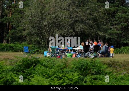 New Forest, Hampshire, Großbritannien. 11. Juli 2020, Familien genießen das heiße Wochenende auf Campingstühlen sitzen Geselligkeit und Treffen für Picknick im Wald jetzt, da Lockdown Regeln entspannt wurden New Forest, Hampshire Credit: Dawn Fletcher-Park/Alamy Live News Stockfoto