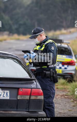 Melbourne, Australien 11. Juli 2020 überprüft ein Polizeibeamter die Details eines Fahrers an einer der Straßensperren auf dem Western Highway in Victoria, um zu versuchen, die Ausbreitung des Corona-Virus in Australiens zweitbevölkerungsreichster Staat einzudämmen. Kredit: Michael Currie/Alamy Live Nachrichten Stockfoto