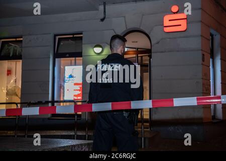 Berlin, Deutschland. Juli 2020. Ein Polizist steht vor einer Bank in der Boxhagener Straße. Unbekannte randalierten in der Boxhagener Straße und um die Jessnerstraße/Weserstraße. Die Fenster der Filiale der Sparkasse waren zerbrochen, die Autofenster waren zerstört, die Autos waren zerkratzt und die verglasten Vordertüren waren beschädigt. (To dpa: 'Unbekannte zerstören Fenster und zerstören Autos - Polizeiaktion') Credit: Paul Zinken/dpa/Alamy Live News Stockfoto