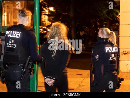 Berlin, Deutschland. Juli 2020. Polizisten führen eine Person in der Jessnerstraße weg. Unbekannte randalierten in der Boxhagener Straße und um die Jessnerstraße/Weserstraße. Die Fenster der Filiale der Sparkasse waren zerbrochen, die Autofenster waren zerstört, die Autos waren zerkratzt und die verglasten Vordertüren waren beschädigt. (To dpa: 'Unbekannte zerstören Fenster und zerstören Autos - Polizeiaktion') Credit: Paul Zinken/dpa/Alamy Live News Stockfoto