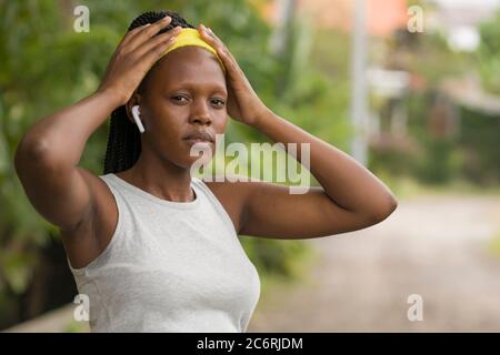 Läufer Mädchen Lifestyle Porträt - jung attraktiv und fit schwarz afro amerikanische Frau Anpassung Haarband vor im Freien Laufen Training auf dem Land Stockfoto