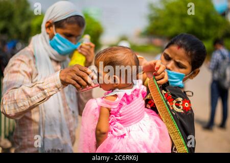 Ghaziabad, Indien. Juli 2020. Die Familie der Migranten lässt ihr Kind in der glühenden Hitze Wasser trinken, während es inmitten des Lockdown zu seinem Heimatort geht.Uttar Pradesh verhängt eine 55-stündige Sperre, bei der alle nicht notwendigen Dienste nach einer rapiden Zunahme der Coronavirus-Fälle in den letzten Tagen ausgesetzt wurden. Kredit: SOPA Images Limited/Alamy Live Nachrichten Stockfoto