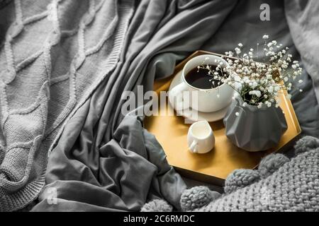 Gemütliches Frühstück im Bett, Tasse Kaffee und Milch auf dem grauen Stoff, Platz für Text. Frühstück im Bett. Stockfoto