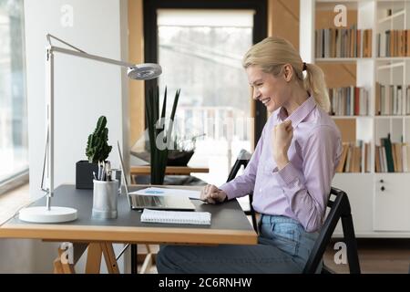 Begeisterte weibliche Angestellte triumphieren mit guten E-Mails auf dem Laptop Stockfoto