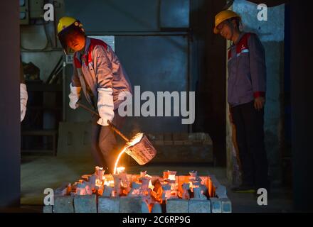 Peking, Chinas Provinz Shanxi. Juli 2020. Guo Zhongping (R) leitet seinen Lehrling Si Peng bei der Herstellung von Eisentöpfen in Jincheng, nordchinesische Provinz Shanxi, 10. Juli 2020. Die traditionelle Art der Herstellung von Jincheng Eisentöpfen beinhaltet Doze von Verfahren. Guo Zhongping, 52, ist Handwerker bei der Herstellung von Eisentöpfen und hauptsächlich für das Gießen zuständig. Quelle: Chai Ting/Xinhua/Alamy Live News Stockfoto