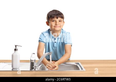 Kind, das sich in einem Waschbecken die Hände wascht und isoliert auf weißem Hintergrund auf die Kamera schaut Stockfoto