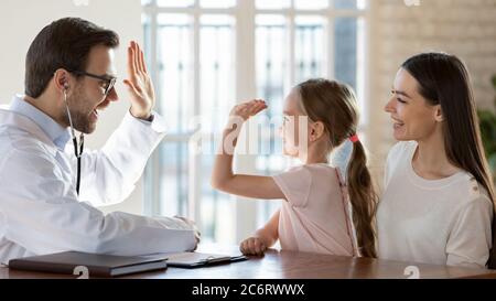 Freundliche Kinderärztin und lächelndes kleines Mädchen, das hohe fünf gibt Stockfoto