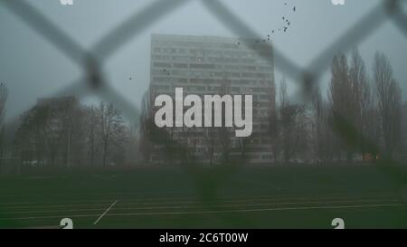 Stadthintergrund. Mehrstöckiges Gebäude am Morgen, im Nebel. Apartmentgebäude hinter Gittern. Ghetto, Unterkunft für die Armen. Konzept Stockfoto