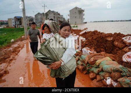 (200712) -- POYANG, 12. Juli 2020 (Xinhua) -- die Freiwilligen Yu Fengying (Front) und Jiang Yunfeng tragen Sandsäcke zum Deich im Dorf Jiangjialing, Stadt Poyang in der Provinz Jiangxi im Osten Chinas, 11. Juli 2020. Aufgrund der anhaltenden starken Regenfälle erhöhte die ostchinesische Provinz Jiangxi ihre Reaktion auf die Überschwemmungskontrolle innerhalb von nur drei Tagen von Stufe III auf Stufe I. Neben Parteimitgliedern der Kommunistischen Partei Chinas (KPCh) und bewaffneten Polizisten, die organisiert sind, um am Kampf gegen die Flut teilzunehmen, widmet sich auch eine freiwillige Gruppe älterer Frauen im Dorf Jiangjialing ihren Bemühungen. Yu Fengying, te Stockfoto