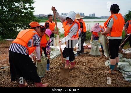 (200712) -- POYANG, 12. Juli 2020 (Xinhua) -- Freiwillige packen Sandsäcke im Dorf Jiangjialing, Stadt Poyang in der Provinz Jiangxi in Ostchina, 11. Juli 2020. Aufgrund der anhaltenden starken Regenfälle erhöhte die ostchinesische Provinz Jiangxi ihre Reaktion auf die Überschwemmungskontrolle innerhalb von nur drei Tagen von Stufe III auf Stufe I. Neben Parteimitgliedern der Kommunistischen Partei Chinas (KPCh) und bewaffneten Polizisten, die organisiert sind, um am Kampf gegen die Flut teilzunehmen, widmet sich auch eine freiwillige Gruppe älterer Frauen im Dorf Jiangjialing ihren Bemühungen. Yu Fengying, Teamleiter der Gruppe, sagte, dass sie ursprünglich waren Stockfoto