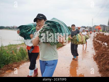 (200712) -- POYANG, 12. Juli 2020 (Xinhua) -- Freiwillige tragen Sandsäcke zum Deich im Dorf Jiangjialing, Stadt Poyang in der Provinz Jiangxi im Osten Chinas, 11. Juli 2020. Aufgrund der anhaltenden starken Regenfälle erhöhte die ostchinesische Provinz Jiangxi ihre Reaktion auf die Überschwemmungskontrolle innerhalb von nur drei Tagen von Stufe III auf Stufe I. Neben Parteimitgliedern der Kommunistischen Partei Chinas (KPCh) und bewaffneten Polizisten, die organisiert sind, um am Kampf gegen die Flut teilzunehmen, widmet sich auch eine freiwillige Gruppe älterer Frauen im Dorf Jiangjialing ihren Bemühungen. Yu Fengying, Teamleiter der Gruppe, sagte, dass sie das tun Stockfoto