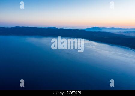 Eine Luftaufnahme eines Salda Sees mit Sonnenaufgang und Silhouette Hügel Hintergrund. Tourismus-Konzept Stockfoto