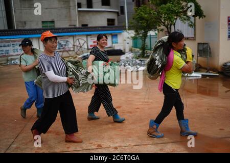 (200712) -- POYANG, 12. Juli 2020 (Xinhua) -- Freiwillige tragen Sandsäcke zum Deich im Dorf Jiangjialing, Stadt Poyang in der Provinz Jiangxi im Osten Chinas, 11. Juli 2020. Aufgrund der anhaltenden starken Regenfälle erhöhte die ostchinesische Provinz Jiangxi ihre Reaktion auf die Überschwemmungskontrolle innerhalb von nur drei Tagen von Stufe III auf Stufe I. Neben Parteimitgliedern der Kommunistischen Partei Chinas (KPCh) und bewaffneten Polizisten, die organisiert sind, um am Kampf gegen die Flut teilzunehmen, widmet sich auch eine freiwillige Gruppe älterer Frauen im Dorf Jiangjialing ihren Bemühungen. Yu Fengying, Teamleiter der Gruppe, sagte, dass sie das tun Stockfoto