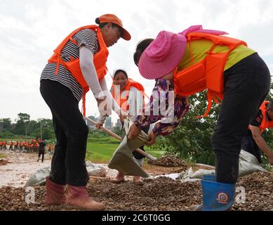 (200712) -- POYANG, 12. Juli 2020 (Xinhua) -- Freiwillige packen Sandsäcke im Dorf Jiangjialing, Stadt Poyang in der Provinz Jiangxi in Ostchina, 11. Juli 2020. Aufgrund der anhaltenden starken Regenfälle erhöhte die ostchinesische Provinz Jiangxi ihre Reaktion auf die Überschwemmungskontrolle innerhalb von nur drei Tagen von Stufe III auf Stufe I. Neben Parteimitgliedern der Kommunistischen Partei Chinas (KPCh) und bewaffneten Polizisten, die organisiert sind, um am Kampf gegen die Flut teilzunehmen, widmet sich auch eine freiwillige Gruppe älterer Frauen im Dorf Jiangjialing ihren Bemühungen. Yu Fengying, Teamleiter der Gruppe, sagte, dass sie ursprünglich waren Stockfoto