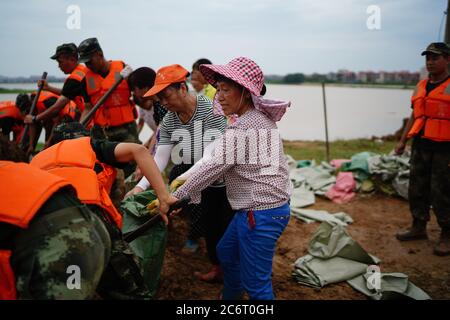 (200712) -- POYANG, 12. Juli 2020 (Xinhua) -- Freiwillige packen Sandsäcke im Dorf Jiangjialing, Stadt Poyang in der Provinz Jiangxi in Ostchina, 11. Juli 2020. Aufgrund der anhaltenden starken Regenfälle erhöhte die ostchinesische Provinz Jiangxi ihre Reaktion auf die Überschwemmungskontrolle innerhalb von nur drei Tagen von Stufe III auf Stufe I. Neben Parteimitgliedern der Kommunistischen Partei Chinas (KPCh) und bewaffneten Polizisten, die organisiert sind, um am Kampf gegen die Flut teilzunehmen, widmet sich auch eine freiwillige Gruppe älterer Frauen im Dorf Jiangjialing ihren Bemühungen. Yu Fengying, Teamleiter der Gruppe, sagte, dass sie ursprünglich waren Stockfoto