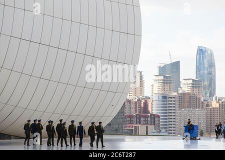 Soldaten gehen an der Front des Heydar Aliyev Zentrums vorbei, das von Zaha Hadid entworfen wurde und das Herzstück der modernen Architektur in Baku Aserbaidschan ist Stockfoto