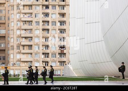 Soldaten gehen an der Front des Heydar Aliyev Zentrums vorbei, das von Zaha Hadid entworfen wurde und das Herzstück der modernen Architektur in Baku Aserbaidschan ist Stockfoto