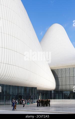 Soldaten gehen an der Front des Heydar Aliyev Zentrums vorbei, das von Zaha Hadid entworfen wurde und das Herzstück der modernen Architektur in Baku Aserbaidschan ist Stockfoto