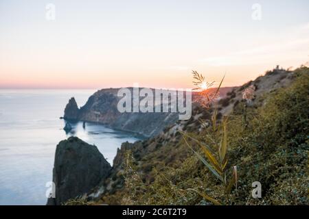 Herbstliche Meereslandschaft mit warmem Sonnenuntergangslicht über felsiger Küste. Ruhiges Meer auf einem Hintergrund von felsigen Küsten. Das Konzept des perfekten Ortes für den Herbst Stockfoto