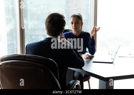 Fokussierter Geschäftsmann, der mit einer Partnerin über Arbeitsfragen spricht. Stockfoto