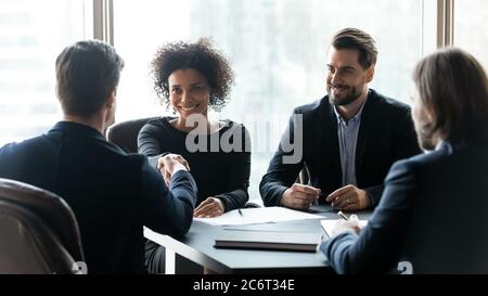 Glückliche multirassische Partner, die Partnerschaft gründen, Hände schütteln bei der Sitzung. Stockfoto