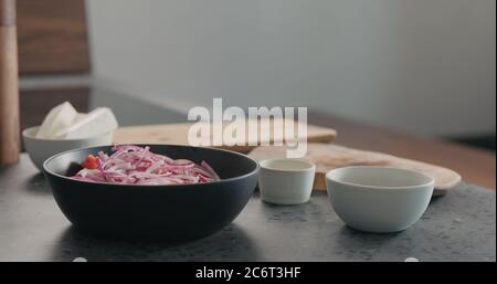 Salz in griechischem Salat in schwarzer Schüssel geben Stockfoto