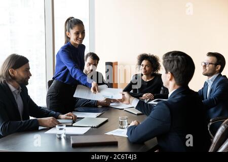 Lächelnder junger Marketing-Spezialist, der Papierberichte ausgibt. Stockfoto