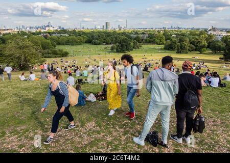 London, Großbritannien. Juli 2020. Die Menschen genießen einen sonnigen Abend auf Primrose Hill mit Blick auf die Stadt. Die „Lockdown“ wird nach wie vor für den Coronavirus (Covid 19) Ausbruch in London gelockert. Kredit: Guy Bell/Alamy Live Nachrichten Stockfoto