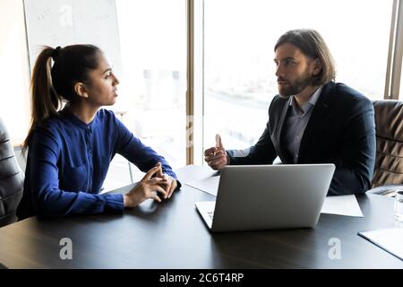 Serious junge männliche Chef im Gespräch mit weiblichen Angestellten. Stockfoto