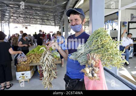 RESEN, MAZEDONIEN - 11. JULI 2020: Junger Mann, der auf einem Bauernmarkt in Resen, Mazedonien, Moutain-Tee, trockenen Fisch und Knoblauch verkauft Stockfoto