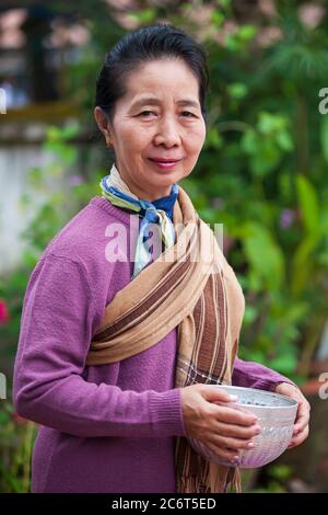 Luang Prabang, Laos - 5. NOVEMBER 2011: Laotische ältere Frau wartet darauf, klebrigen Reis in der Morgenalmosenzeremonie an buddhistische Mönche zu geben. Stockfoto