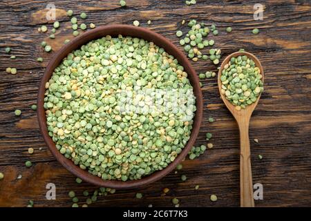 Trocken grüne Erbsen in einer Platte auf einem braunen Holz- Hintergrund. Bohnen für nahrhafte Suppe Stockfoto