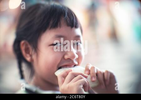 Asiatische Kind Mädchen essen etwas Brot mit Lächeln und glücklich Stockfoto