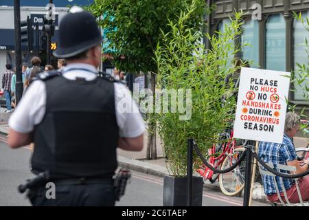 Juli 2020, mit Lockdown Gesetze entspannt, Northcote Road in Clapham ist Fußgängerzone für Restaurants und Bars als Polizist patrouilliert Stockfoto