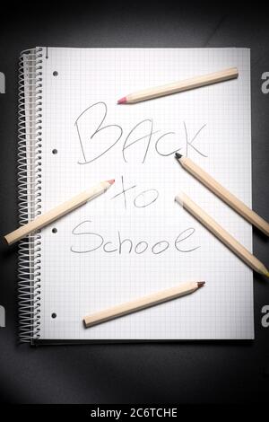 Flache Ansicht von weißem Notizbuch, Farbstifte und Bleistiftspitzer auf einem Tisch. Vorbereitung auf eine Schule. Zurück zur Schule. Stockfoto