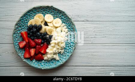 Gesundes Sommerfrühstück. Hüttenkäse mit Erdbeer-Heidelbeerbanane und Honig. Wunderschönes Frühstück Stockfoto