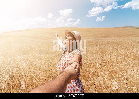 Schöne Frau Hand in einem Feld mit blauem Himmel und Wolken Hintergrund halten. Romantik und ländliches Konzept. Hochwertige Fotos Stockfoto