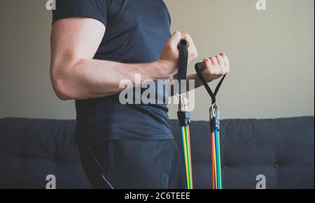 Mann macht Übungen mit Widerstandsbändern zu Hause. Stockfoto