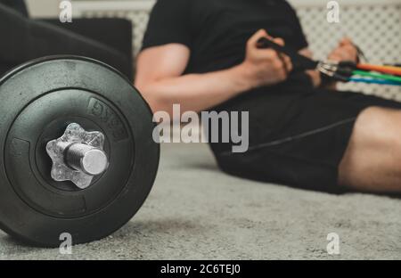 Mann macht Übungen mit Widerstandsbändern zu Hause. Home Fitness-Trainingskonzept. Stockfoto