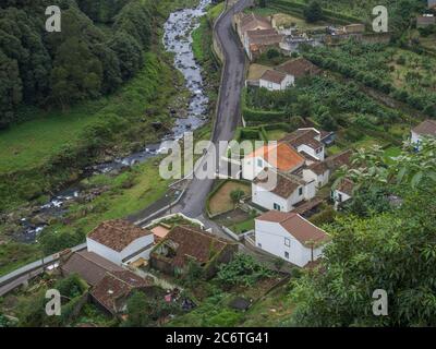 Luftaufnahme des kleinen Dorfes Faial da Terra mit kaskadierenden Fluss, Sao Miguel, Azoren. Stockfoto