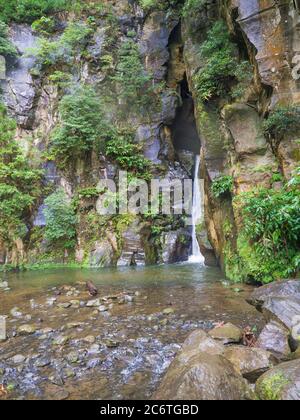 Salto do Cabrito schöner Wasserfall am Wanderweg fällt ein aus Felshöhle in grünen Wald, Sao Miguel, Azoren, Portugal Stockfoto