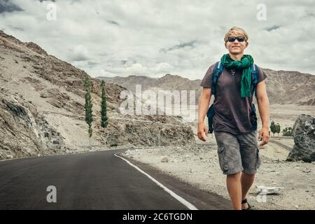 Reisender junger Mann zu Fuß durch die Bergstraße in indischen Himalaya-Bergen. Weltreise – Konzept. Stockfoto