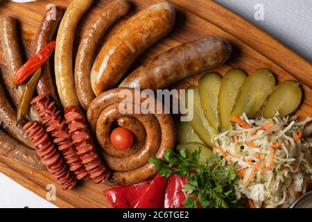Gegrillte Wurst mit eingelegtem Kohl, Tomaten und Gurke. Flach liegend Stockfoto