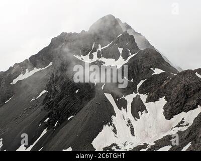 Die schwarzen Berge und Gipfel bedeckt mit weißem Schnee an nebligen Tagen im Jade Dragon Mountain in Yunnan in China Stockfoto