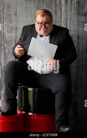 Fat Geschäftsmann mit Analyse-Chart zeigt die aktuelle Position auf der Ölindustrie, depressive Mann in verzweifelten Stockfoto