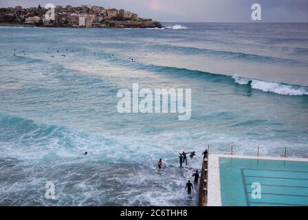 Schwimmer Surfer in Neoprenanzügen spielen in Wellen am Pool am Bondi Beach Stockfoto