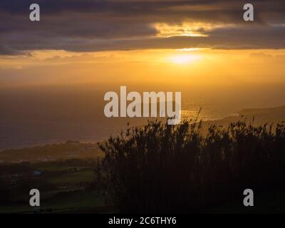 Luftaufnahme von Vila Franca do Campo Stadt vulkanische Insel während orange Sonnenuntergang mit Wolken, contre-jour Licht, Sao Miguel Insel, Azoren, Portugal Stockfoto