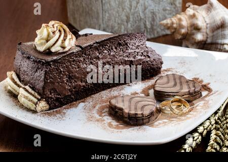 Schokoladenkuchen Kekse Gold Ringe valentinstag Jubiläum Lebensmittel Dessert Teller Mousse Sahne Zuckerguss Stockfoto