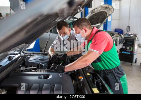 Der Autodienstmitarbeiter führt die Diagnose und die Reparatur des Fahrzeugs durch Stockfoto